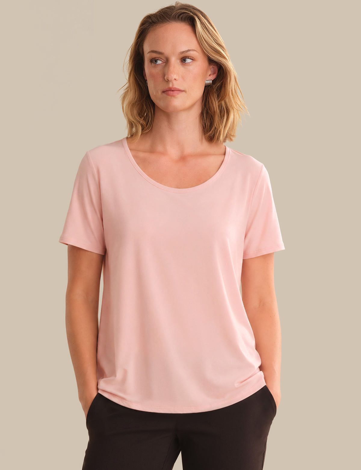 Woman wearing a pink t-shirt against a beige background