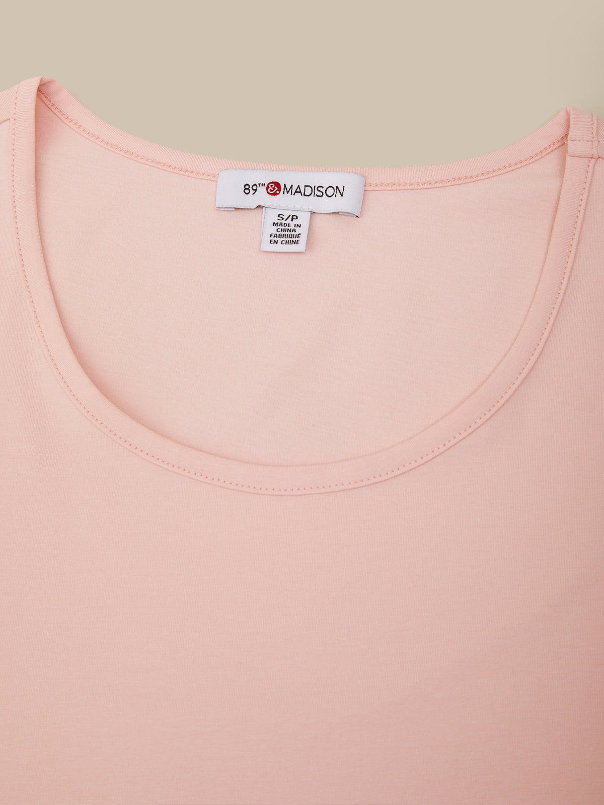 Close-up of a pink garment with a brand label on a beige background