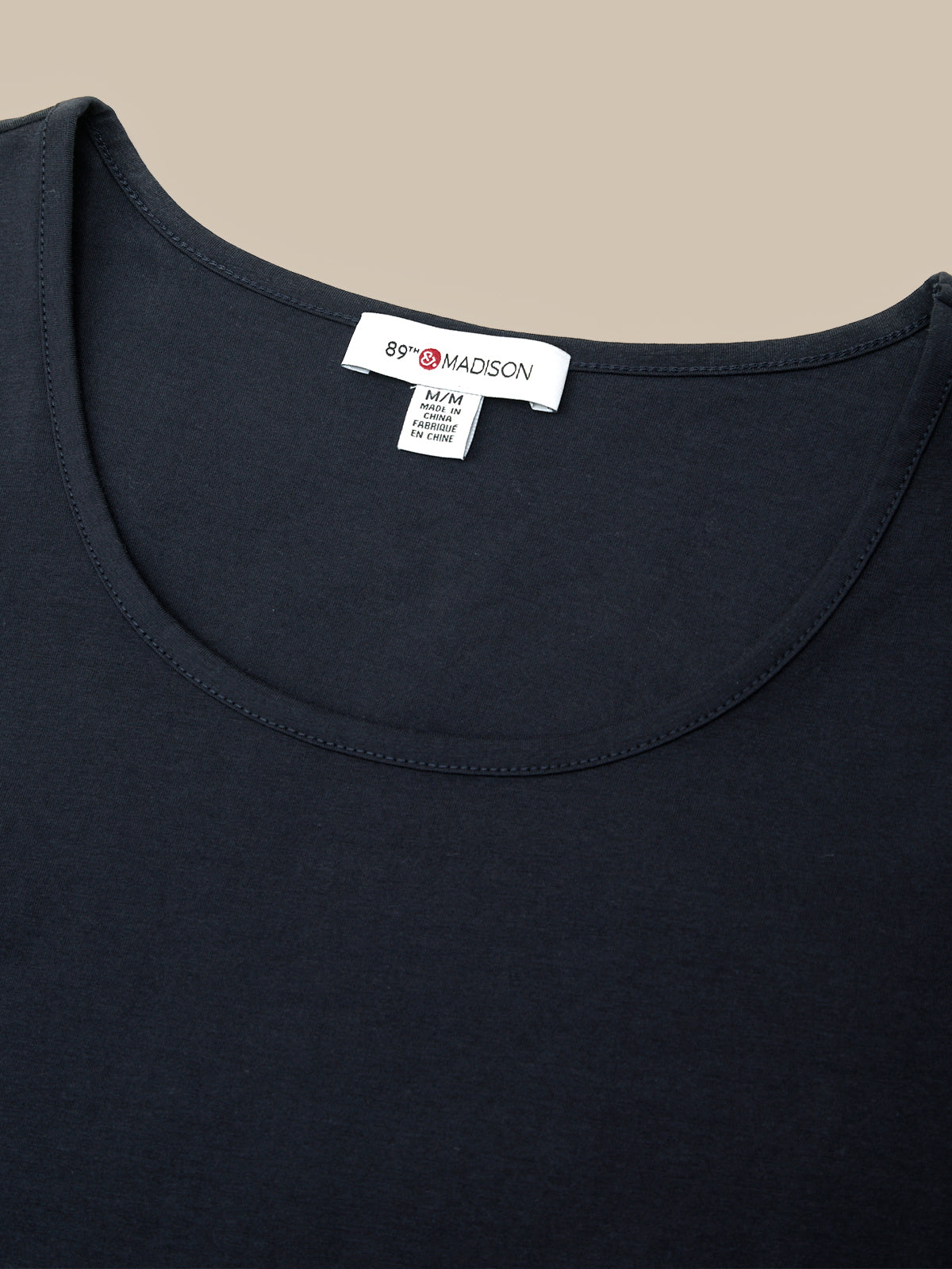 Close-up of a black scoop-neck t-shirt with a visible white neck label reading '89 MADSON'.