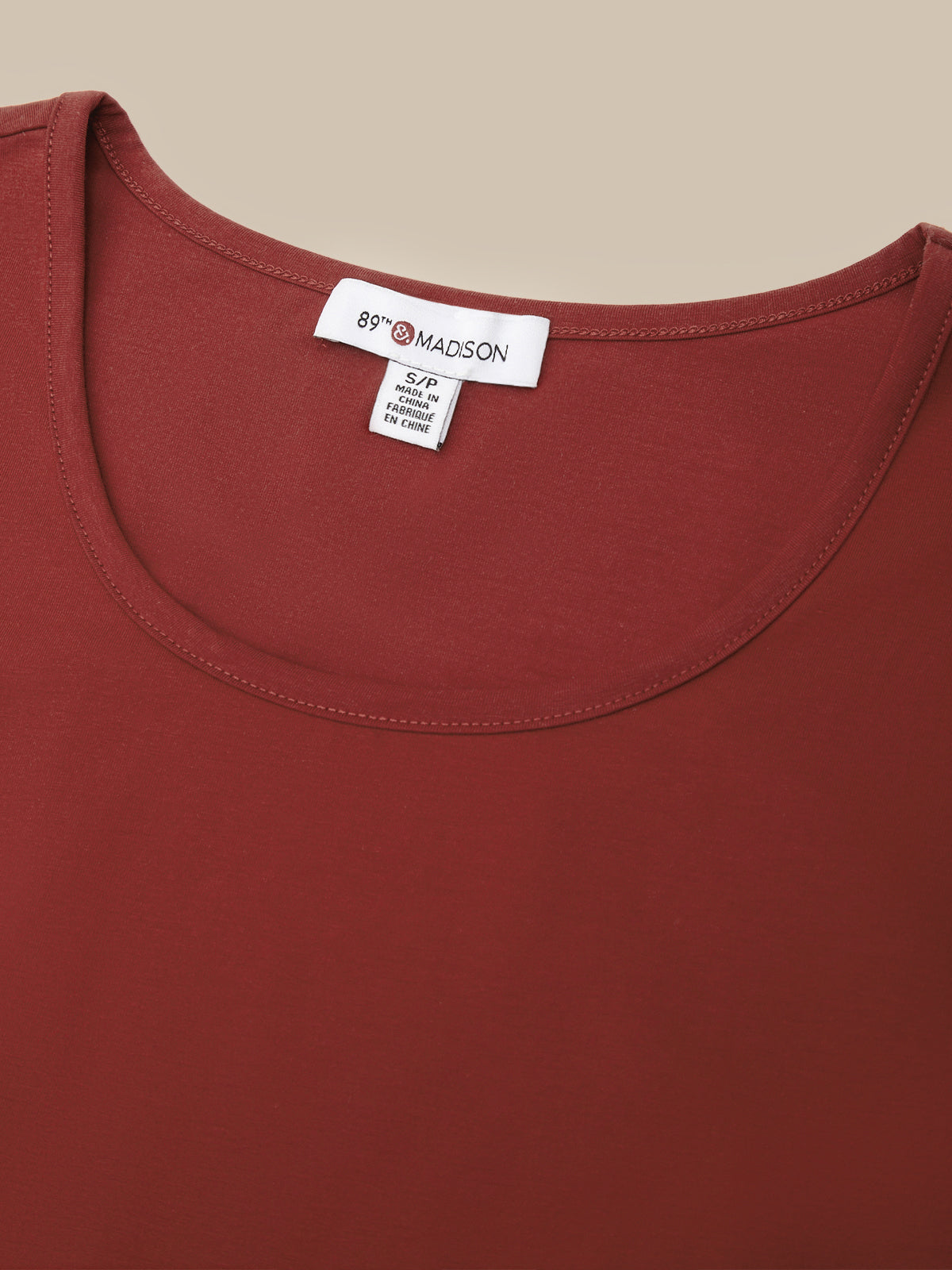 Close-up of a rust red scoop-neck top showing the inner neck label which reads '89TH MADSON'.