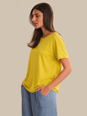 Woman wearing a yellow t-shirt and blue jeans on a beige background