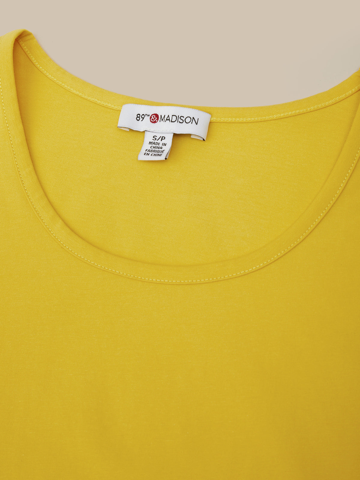 Close-up of a yellow garment with a brand label on a beige background