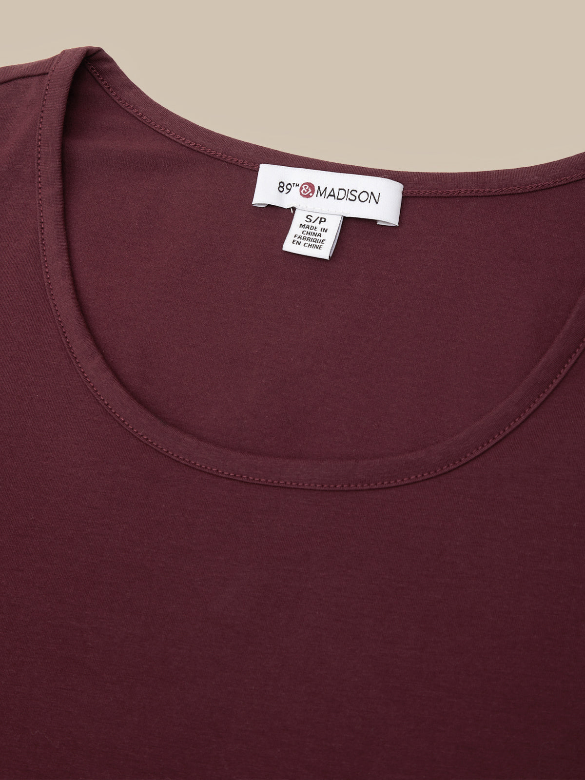 Close-up of a scoop-neck t-shirt in burgundy, showing the inside neck label which reads '89 MADISON'.