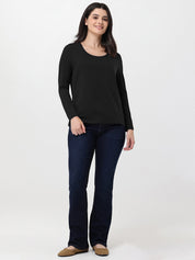 Woman wearing a black long-sleeve top and dark blue jeans on a white background