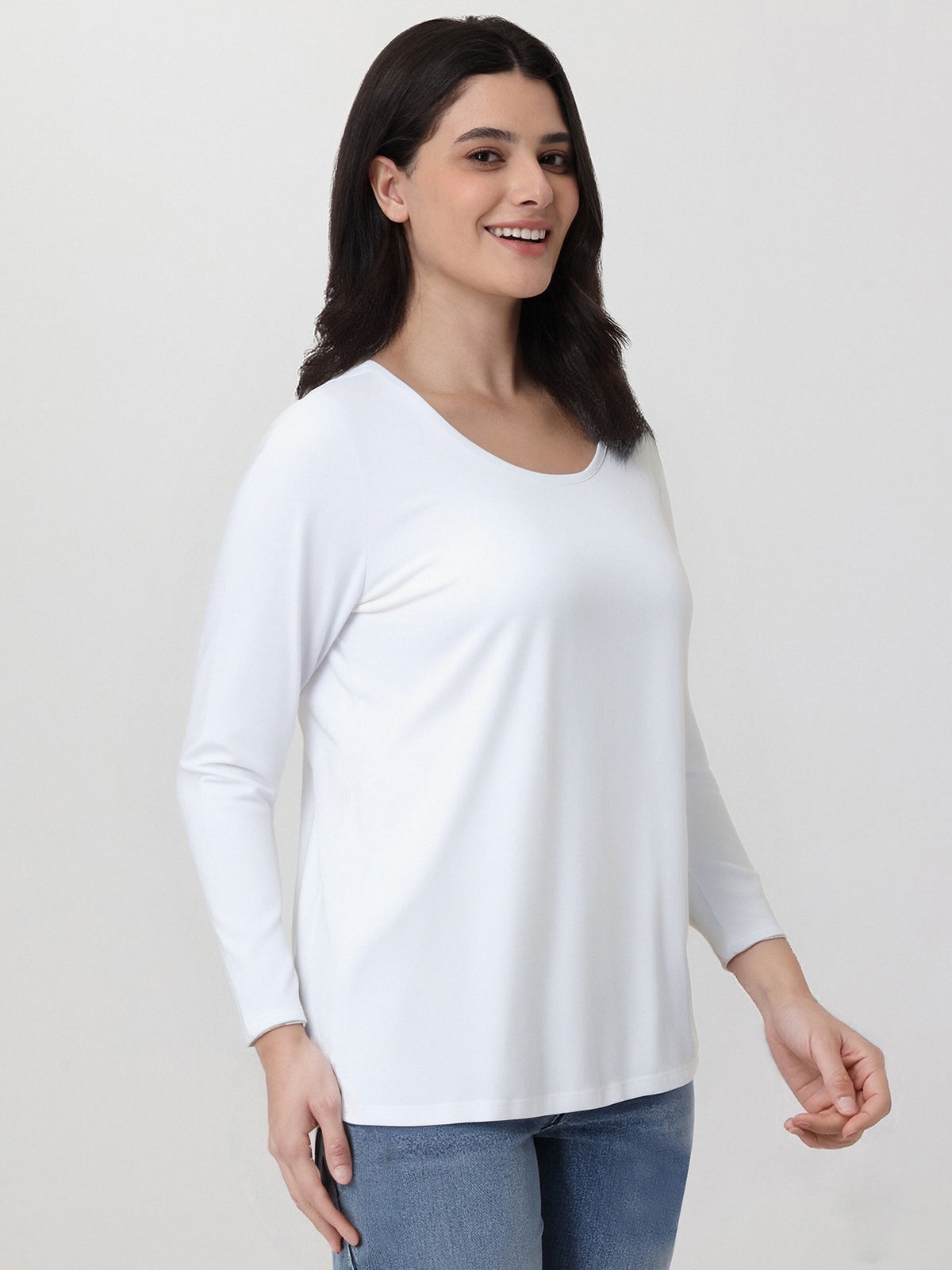 Woman wearing a white long-sleeve top against a plain background