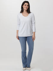 Woman wearing a white long-sleeve top and blue jeans on a white background