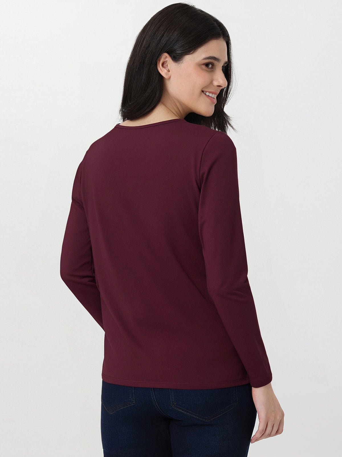 Woman wearing a burgundy long-sleeve top on a white background