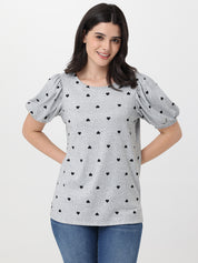 Woman wearing a gray top with black heart patterns on a white background
