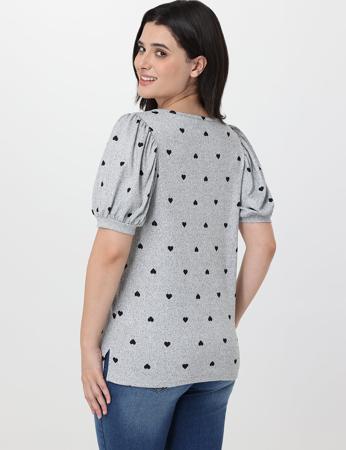 Woman wearing a gray blouse with black heart patterns on a white background