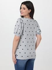 Woman wearing a gray blouse with black heart patterns on a white background