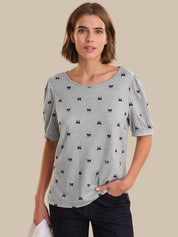 Woman wearing a gray t-shirt with black bow pattern on a beige background