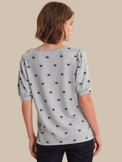 Woman wearing a gray blouse with black bow pattern on a beige background