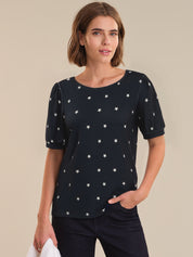 Woman wearing a navy top with star pattern against a beige background