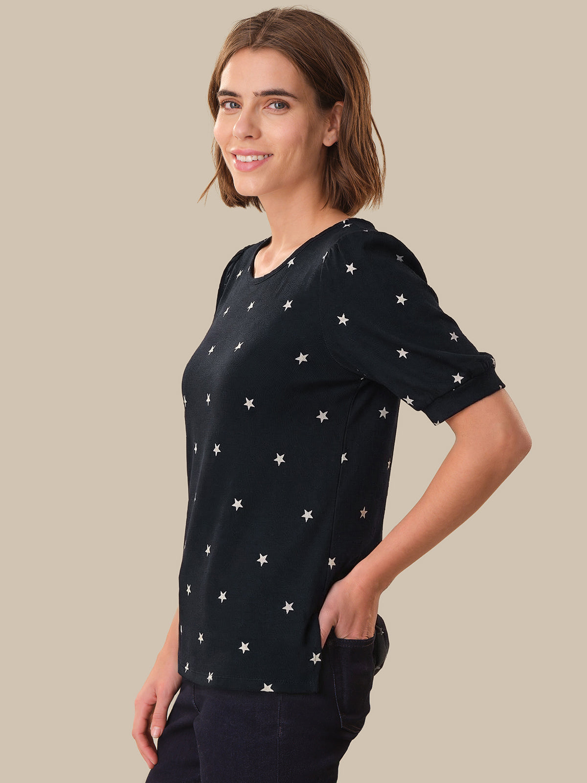 Woman wearing a navy t-shirt with star patterns on a beige background