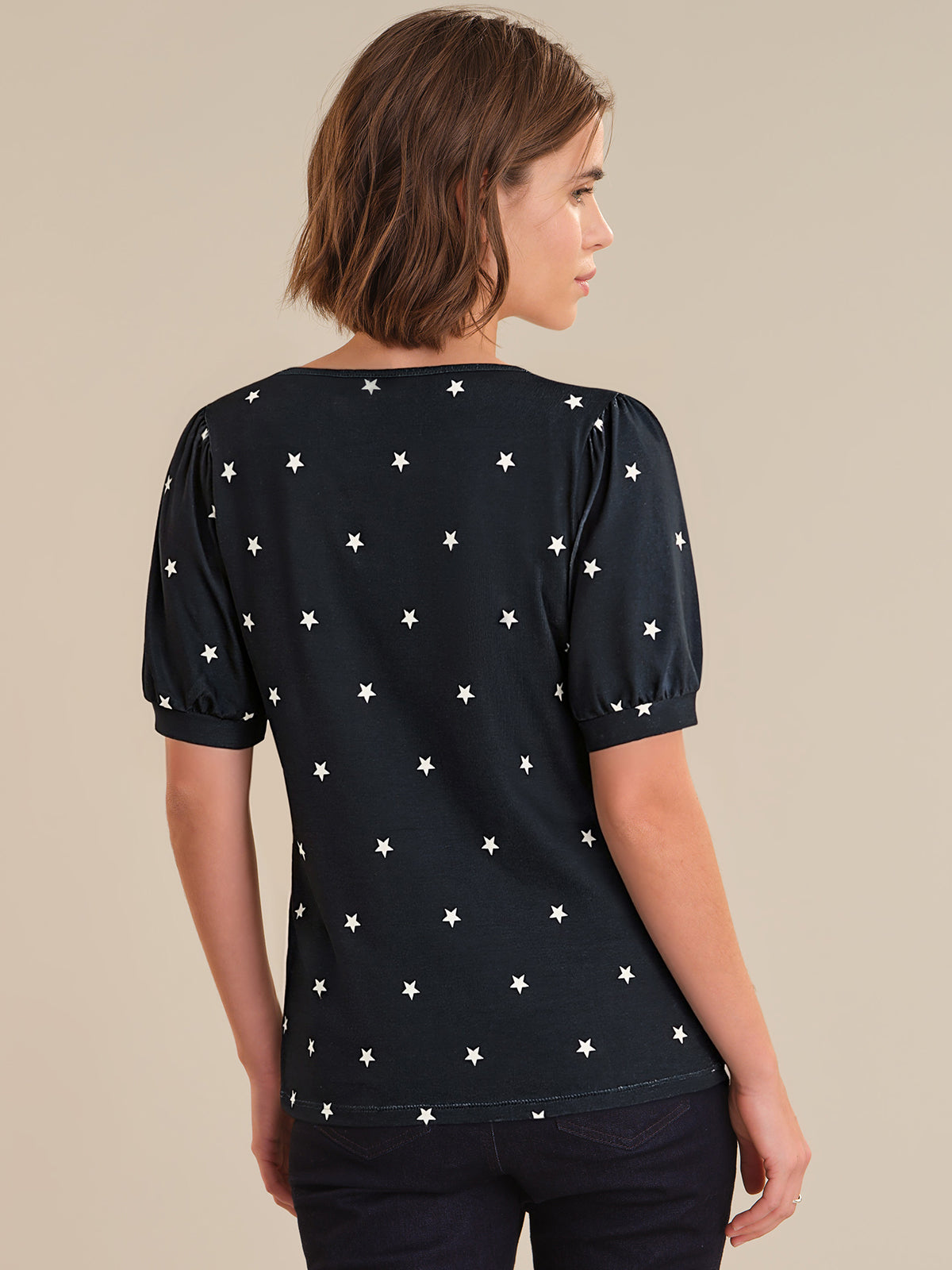 Woman wearing a navy top with white star pattern on a beige background