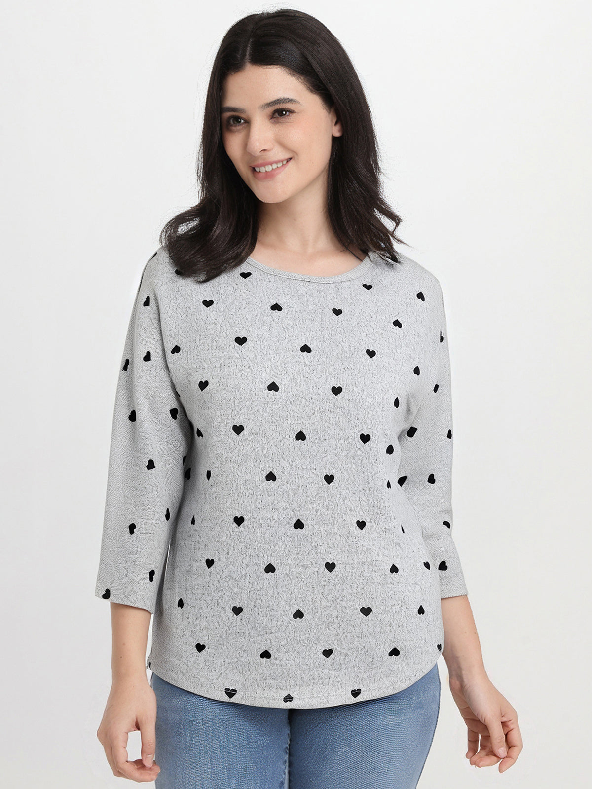 Woman wearing a gray sweater with black heart patterns on a white background