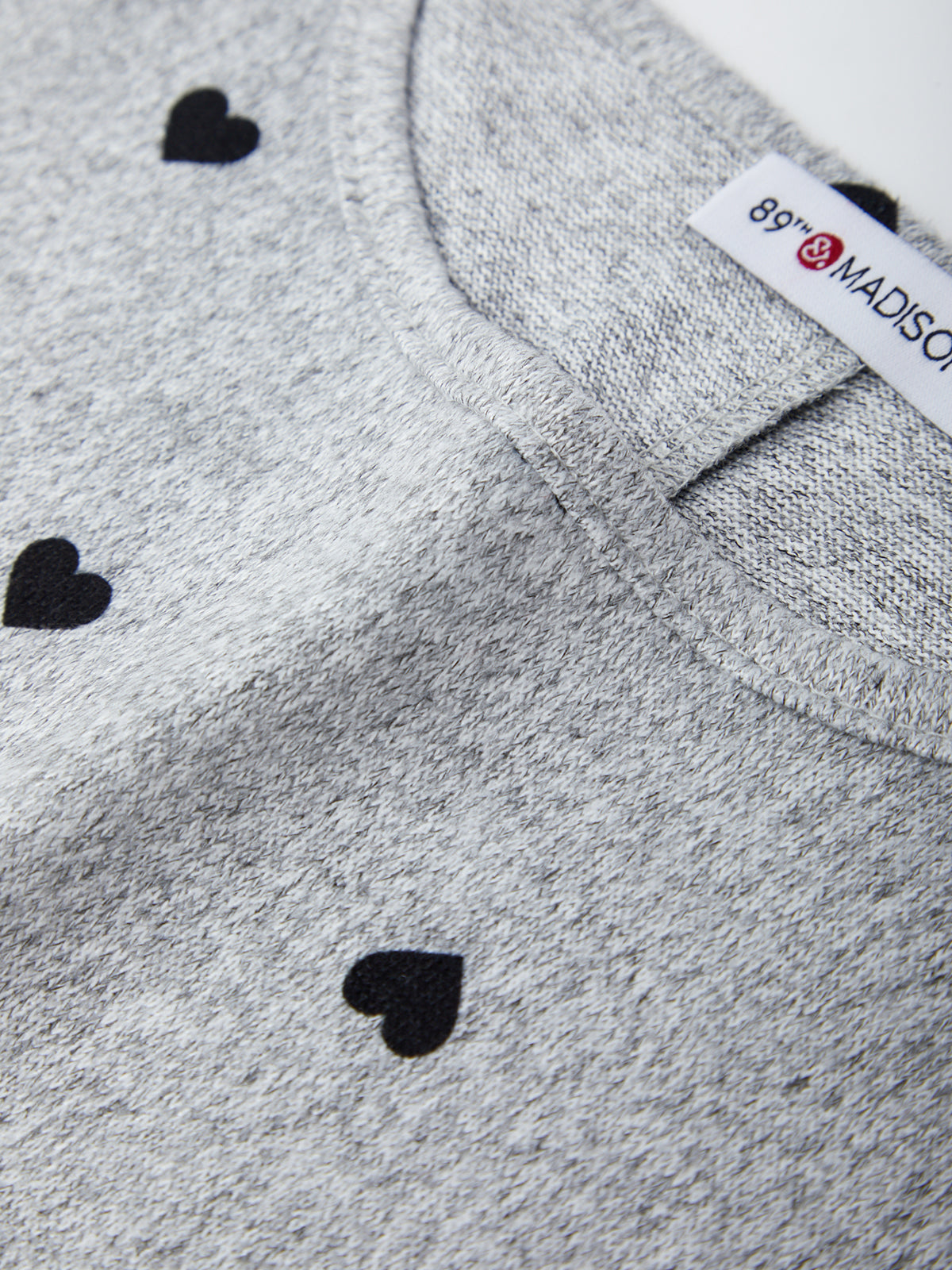 Gray sweater with black heart patterns and a visible brand label.