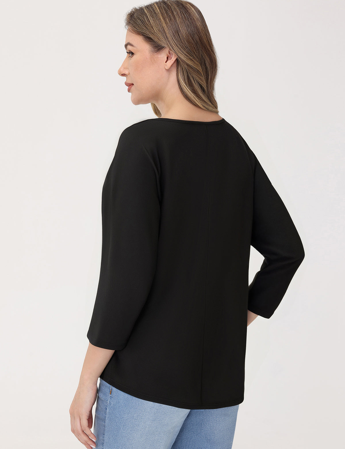 Woman wearing a black top and blue jeans on a white background