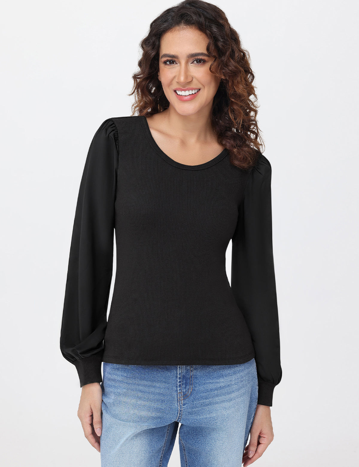 Woman wearing a black long-sleeve top and blue jeans on a white background
