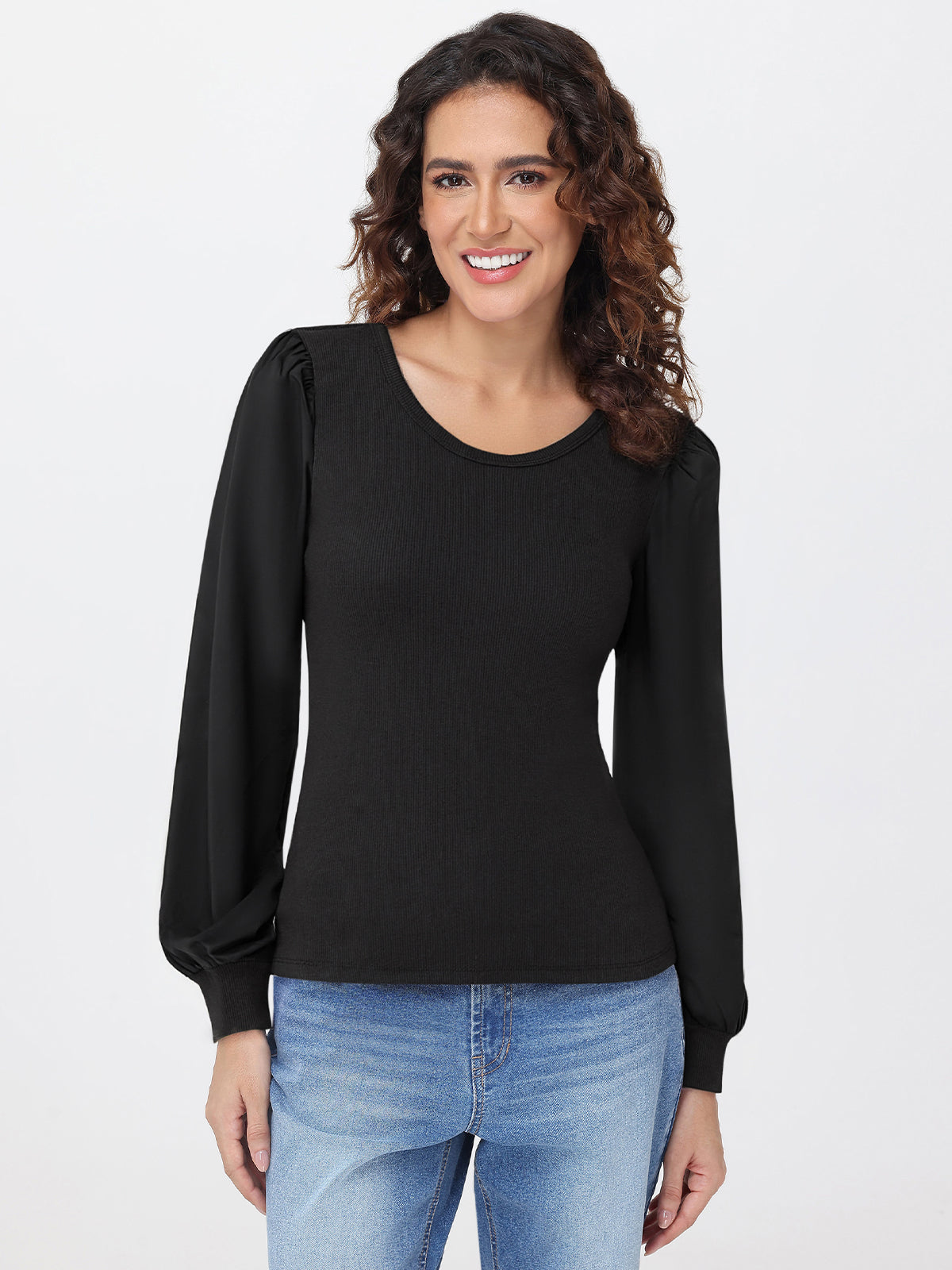 Woman wearing a black long-sleeve top and blue jeans on a white background