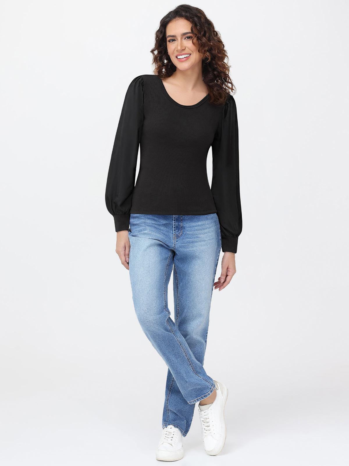Woman wearing a black long-sleeve top and blue jeans on a white background