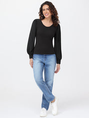 Woman wearing a black long-sleeve top and blue jeans on a white background