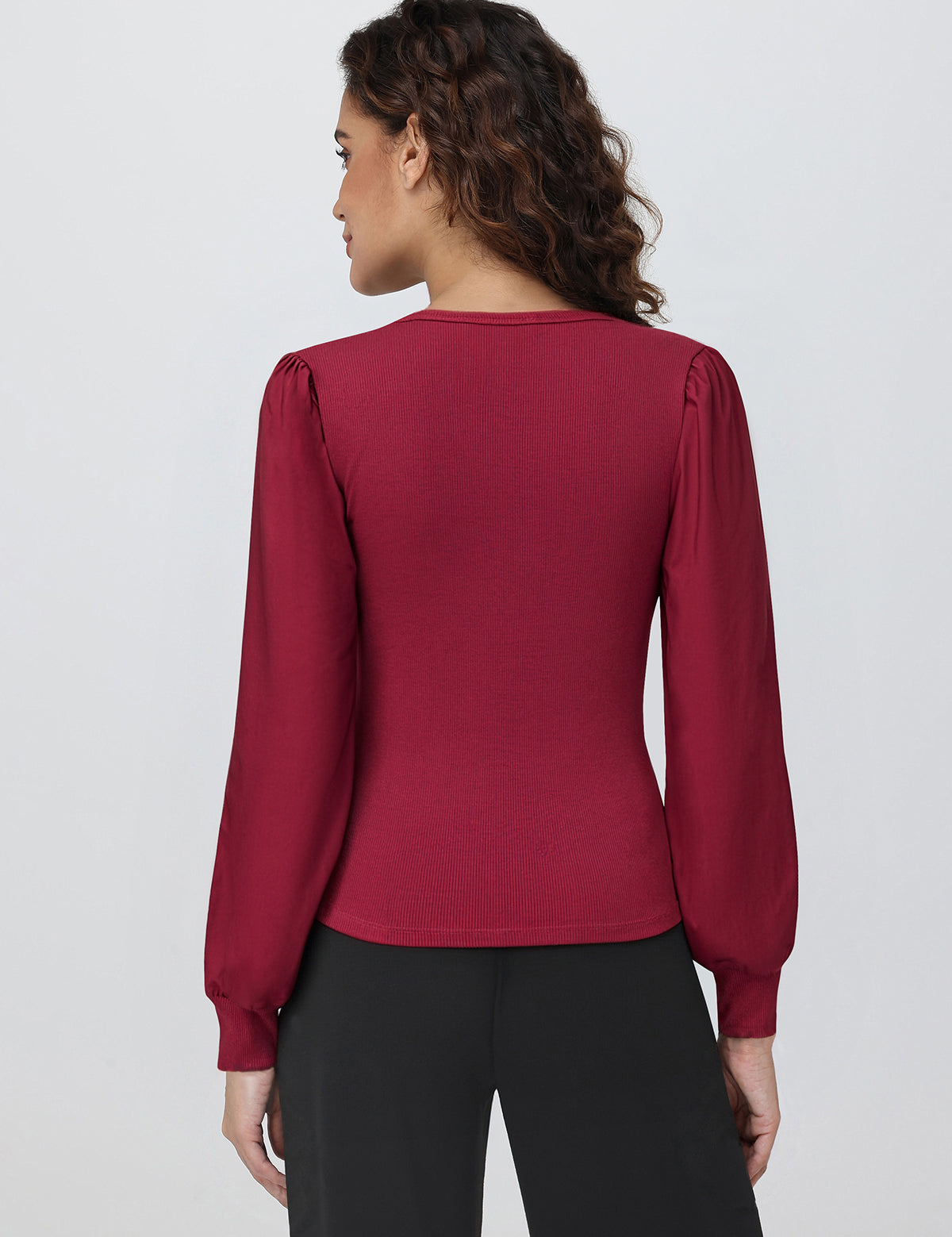 Woman wearing a burgundy long-sleeve top against a white background