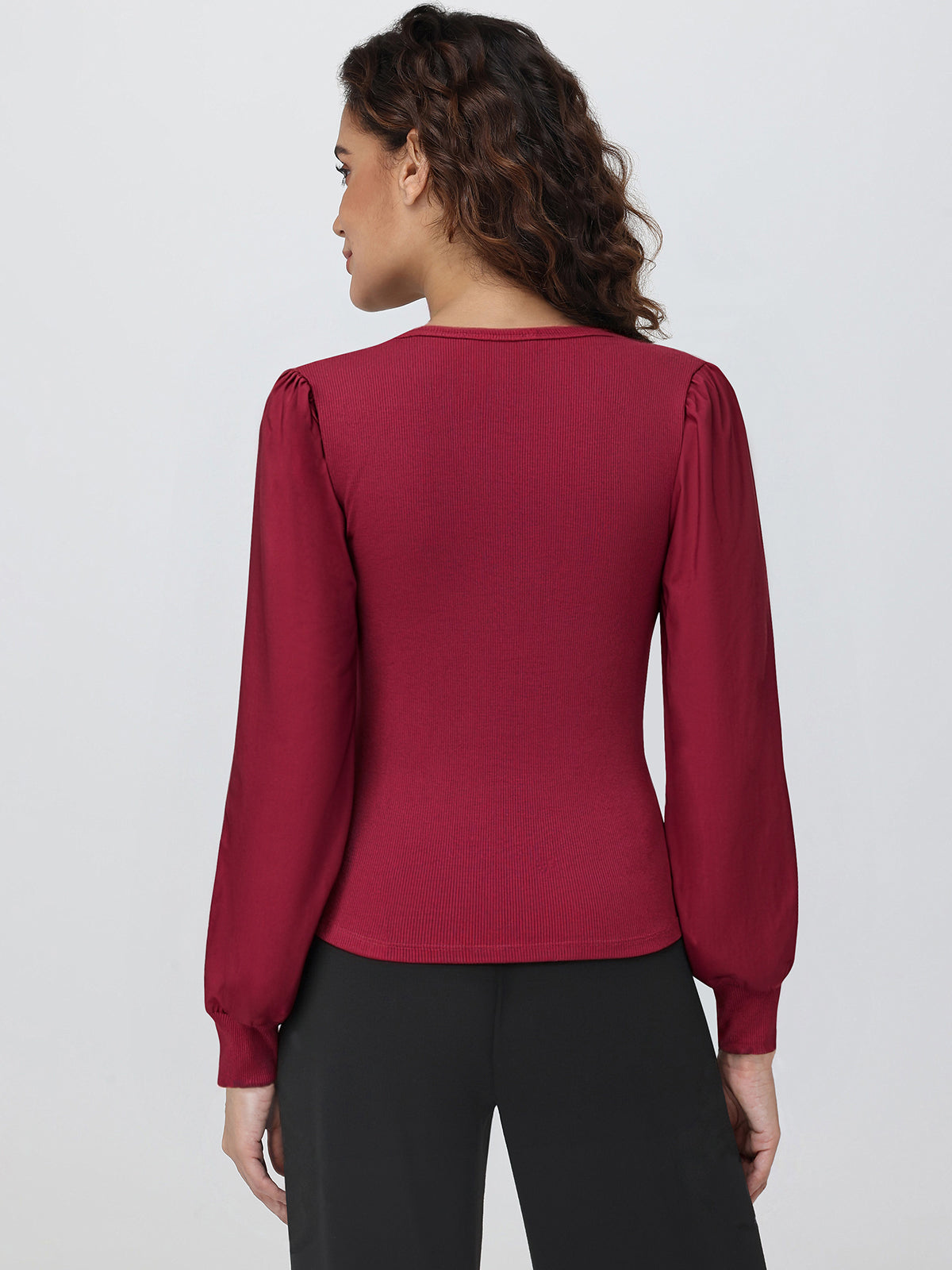 Woman wearing a burgundy long-sleeve top against a white background