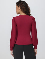 Woman wearing a burgundy long-sleeve top against a white background