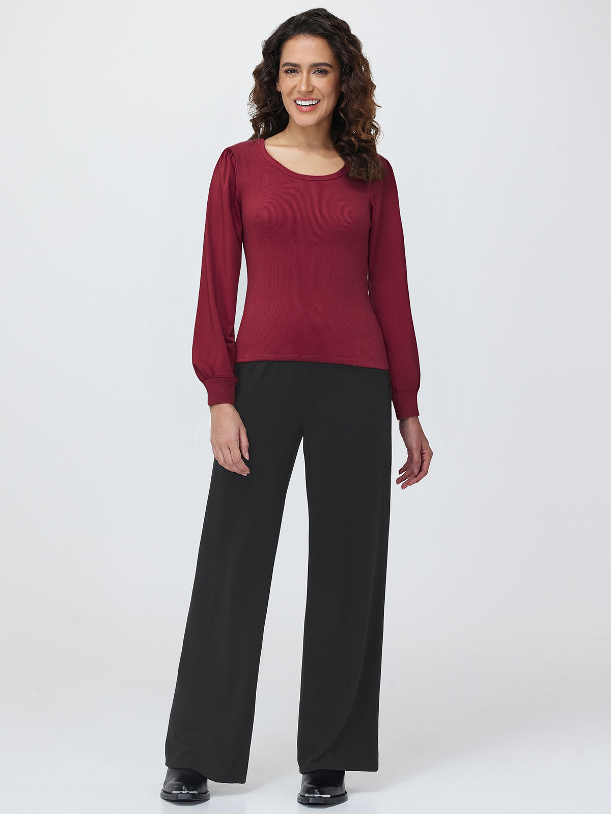 Woman wearing a burgundy top and black pants on a white background