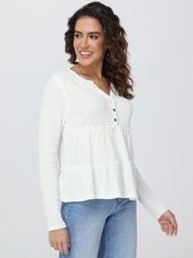 Woman wearing a white blouse with a subtle pattern on a plain background