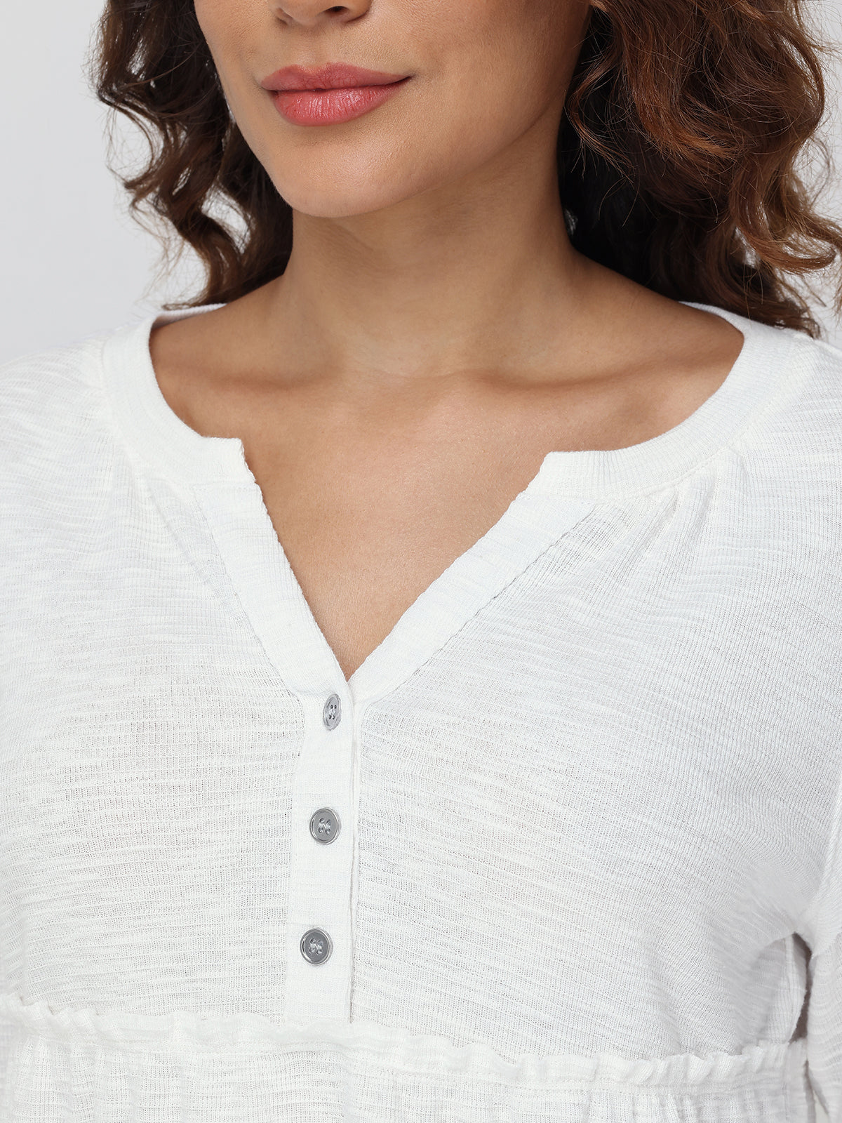 Close-up of a person wearing a white blouse with buttons.