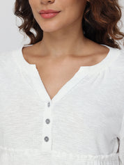 Close-up of a person wearing a white blouse with buttons.