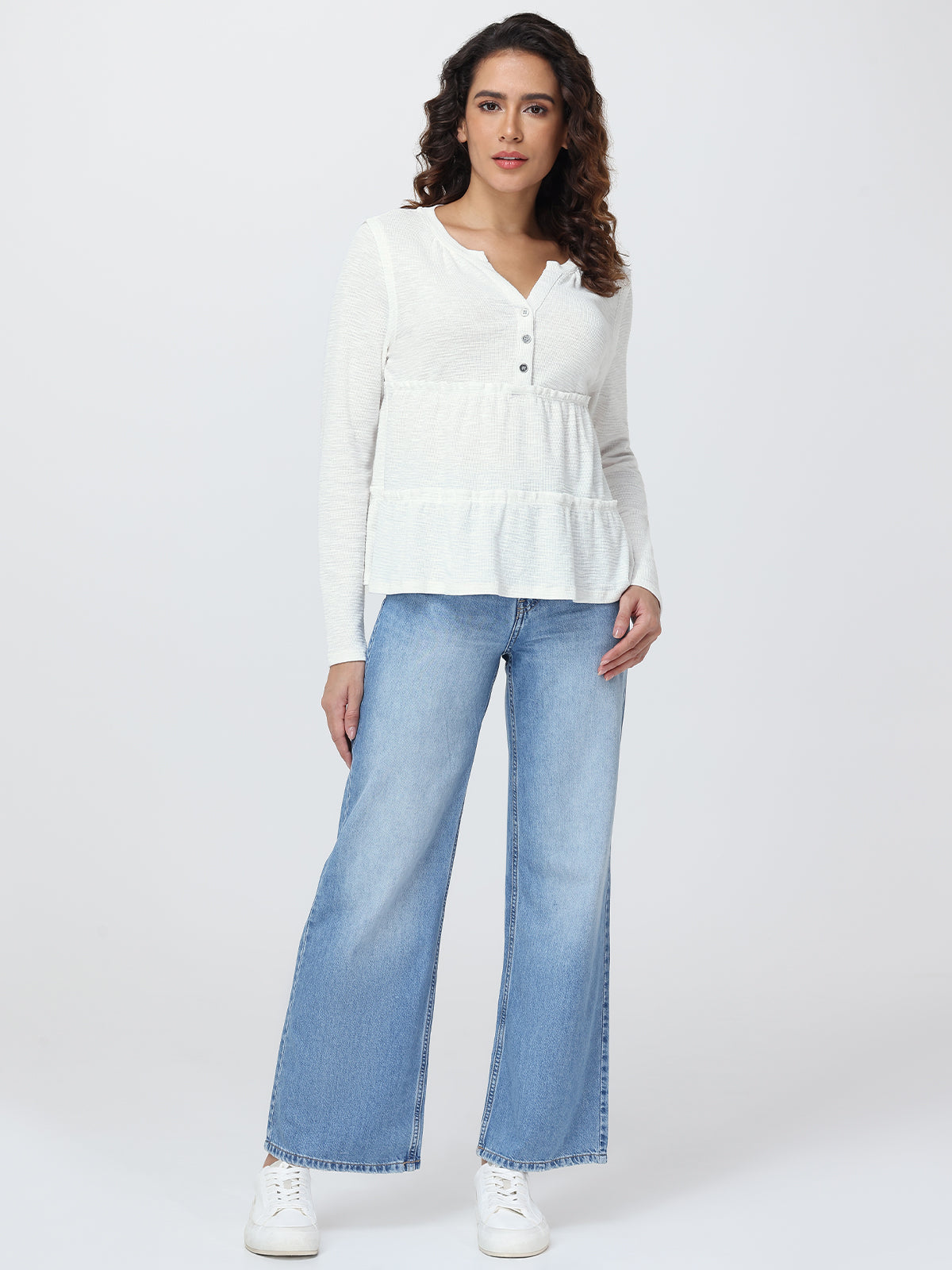 Woman wearing a white blouse and blue jeans on a white background
