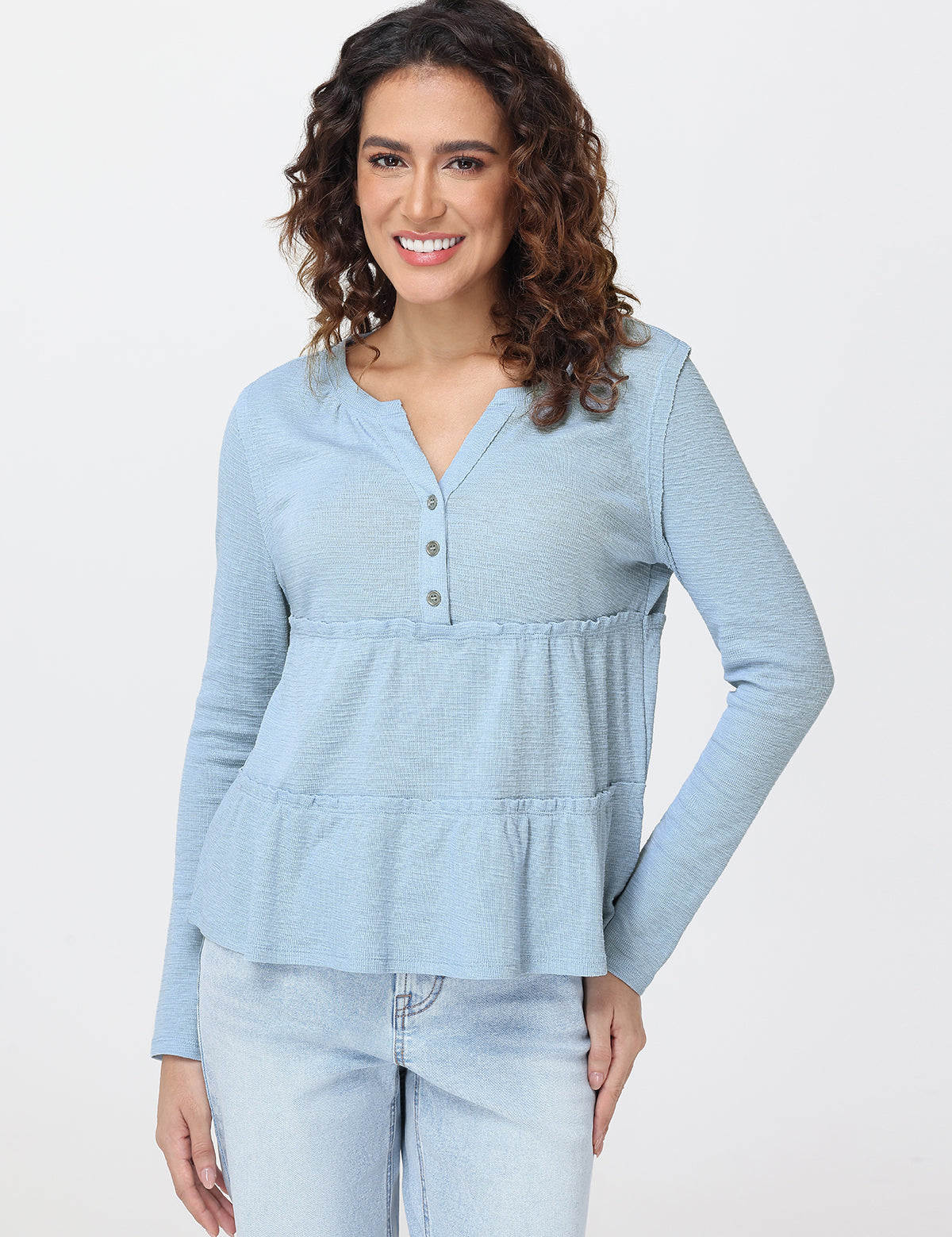 Woman wearing a light blue long-sleeve top with a peplum waist on a white background