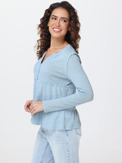 Woman wearing a light blue long-sleeve top and jeans on a white background