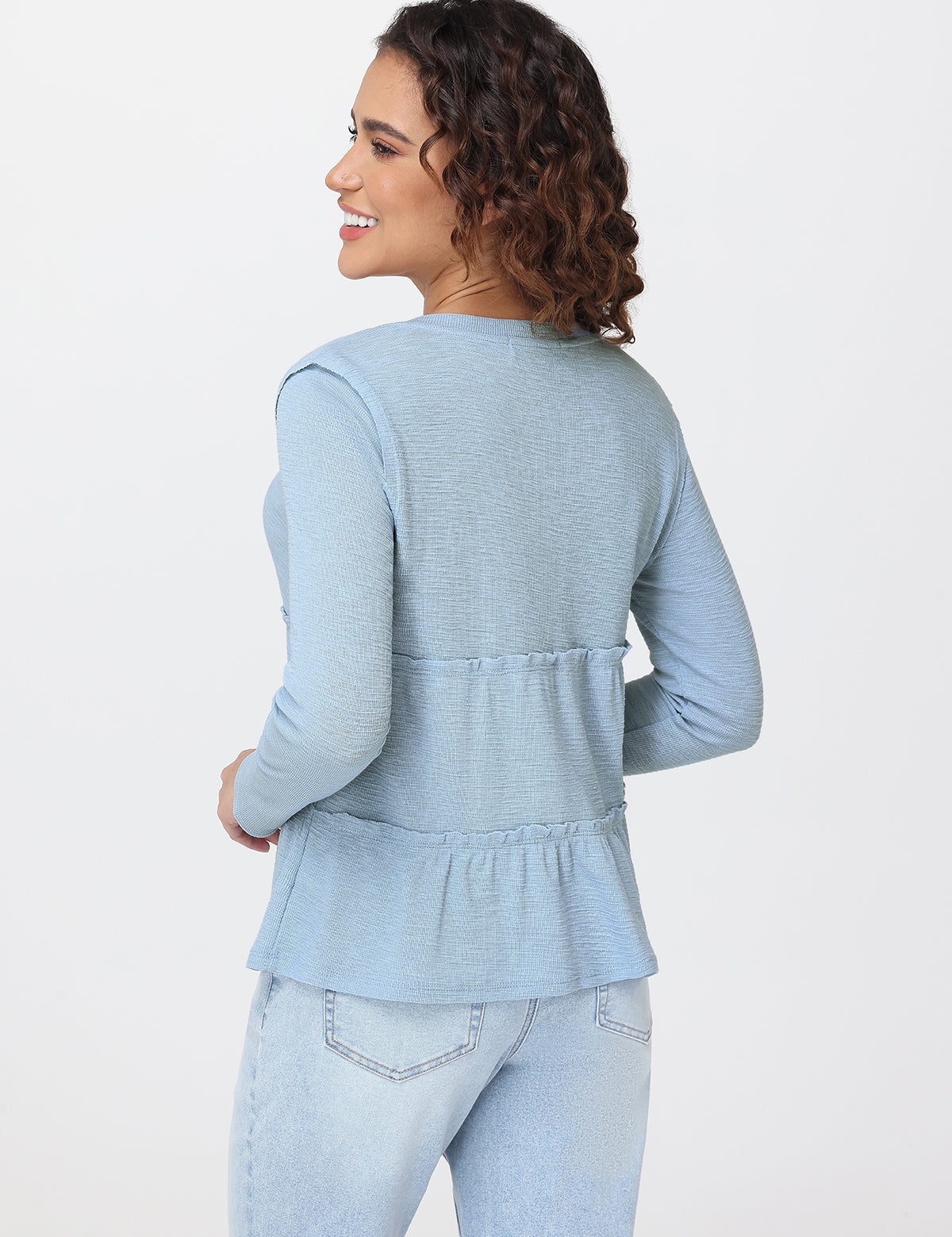 Woman wearing a light blue peplum top and jeans on a white background