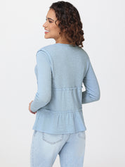 Woman wearing a light blue peplum top and jeans on a white background