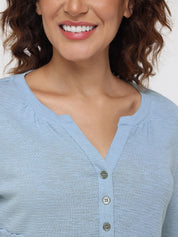 Close-up of a person wearing a light blue button-up shirt against a neutral background