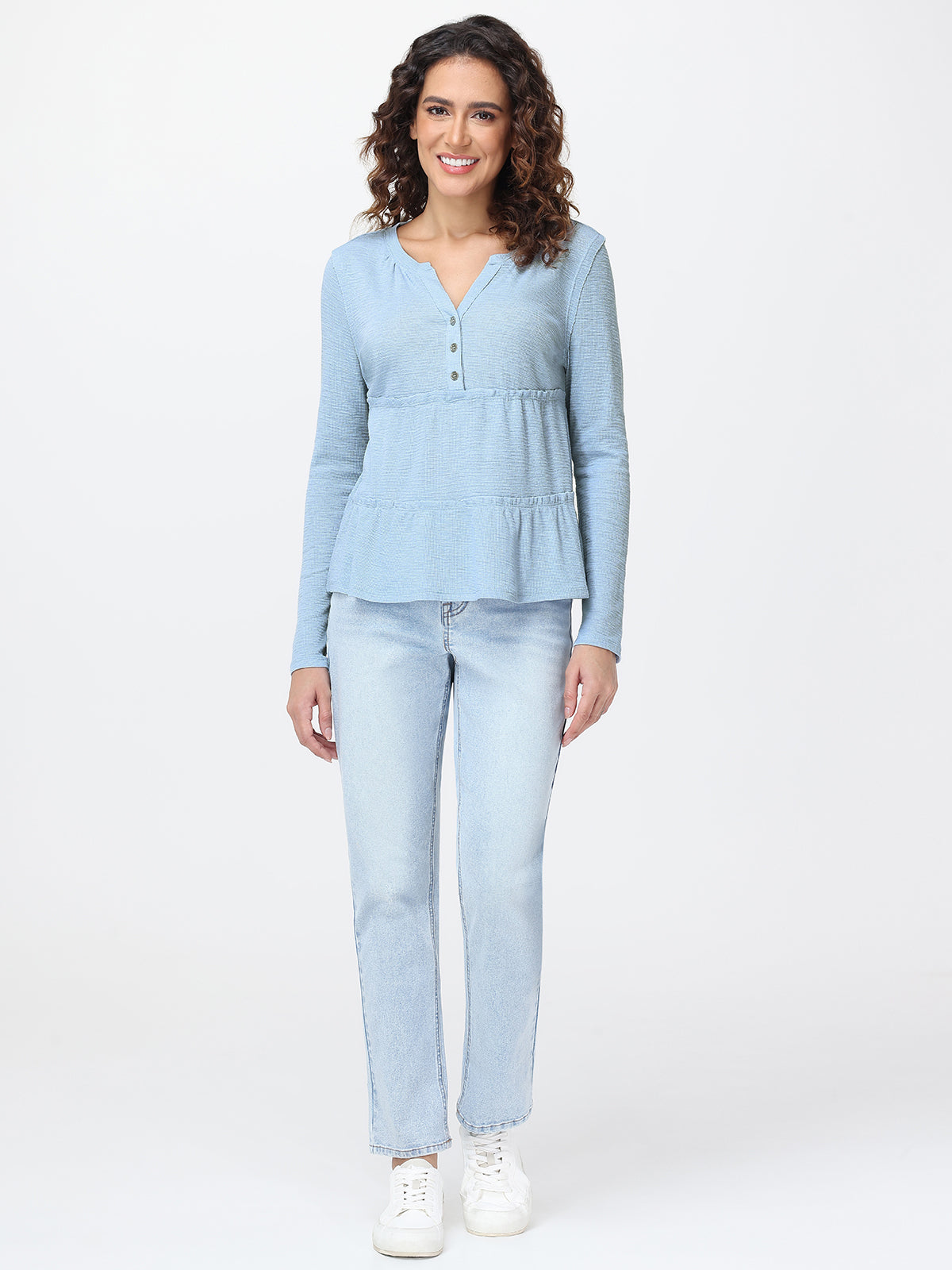 Woman wearing a light blue long-sleeve top and jeans on a white background