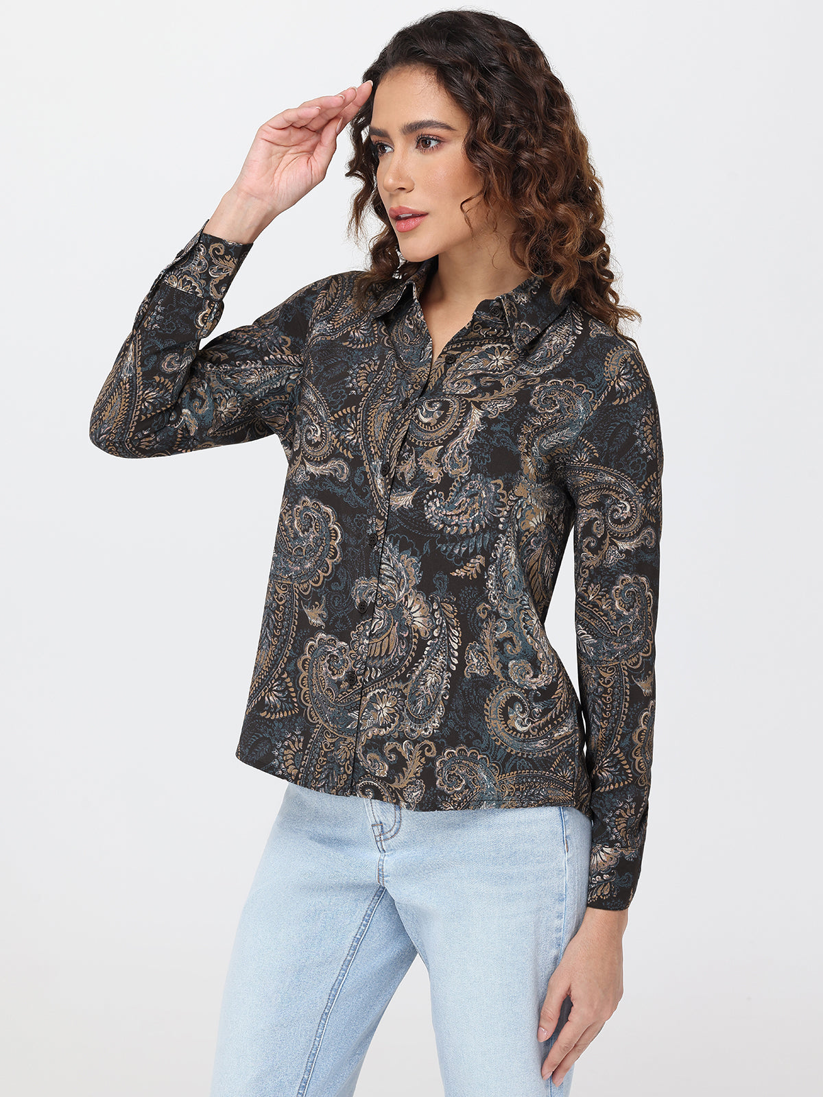 Woman wearing a black patterned shirt and light blue jeans on a white background