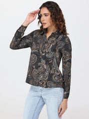 Woman wearing a black patterned shirt and light blue jeans on a white background