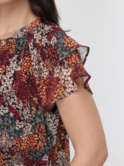 Multicolored patterned top worn by a person on a white background