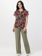 Woman wearing a patterned top and green pants on a white background