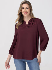 Woman wearing a burgundy blouse with a plain background