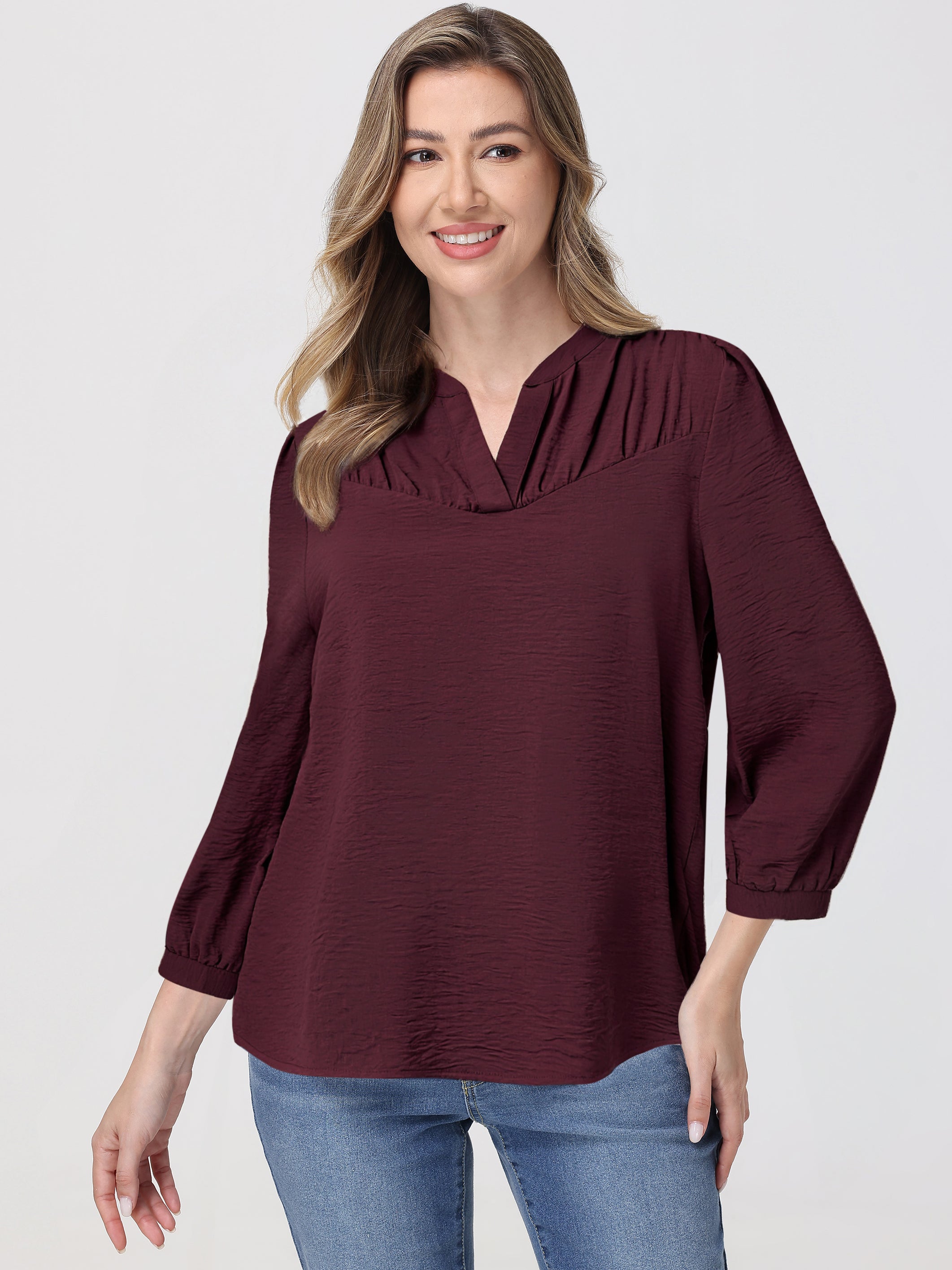 Woman wearing a burgundy blouse with a plain background
