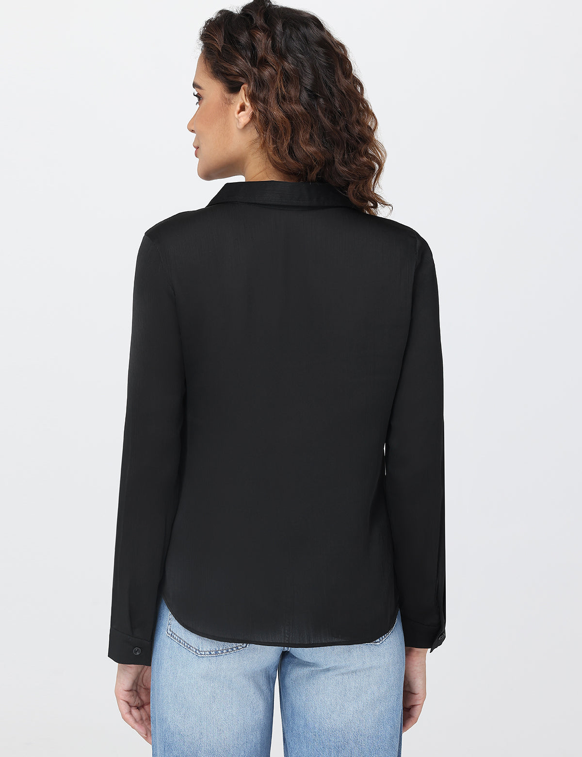 Woman wearing a black shirt and light blue jeans on a white background