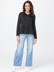 Woman wearing a black shirt and light blue jeans on a white background