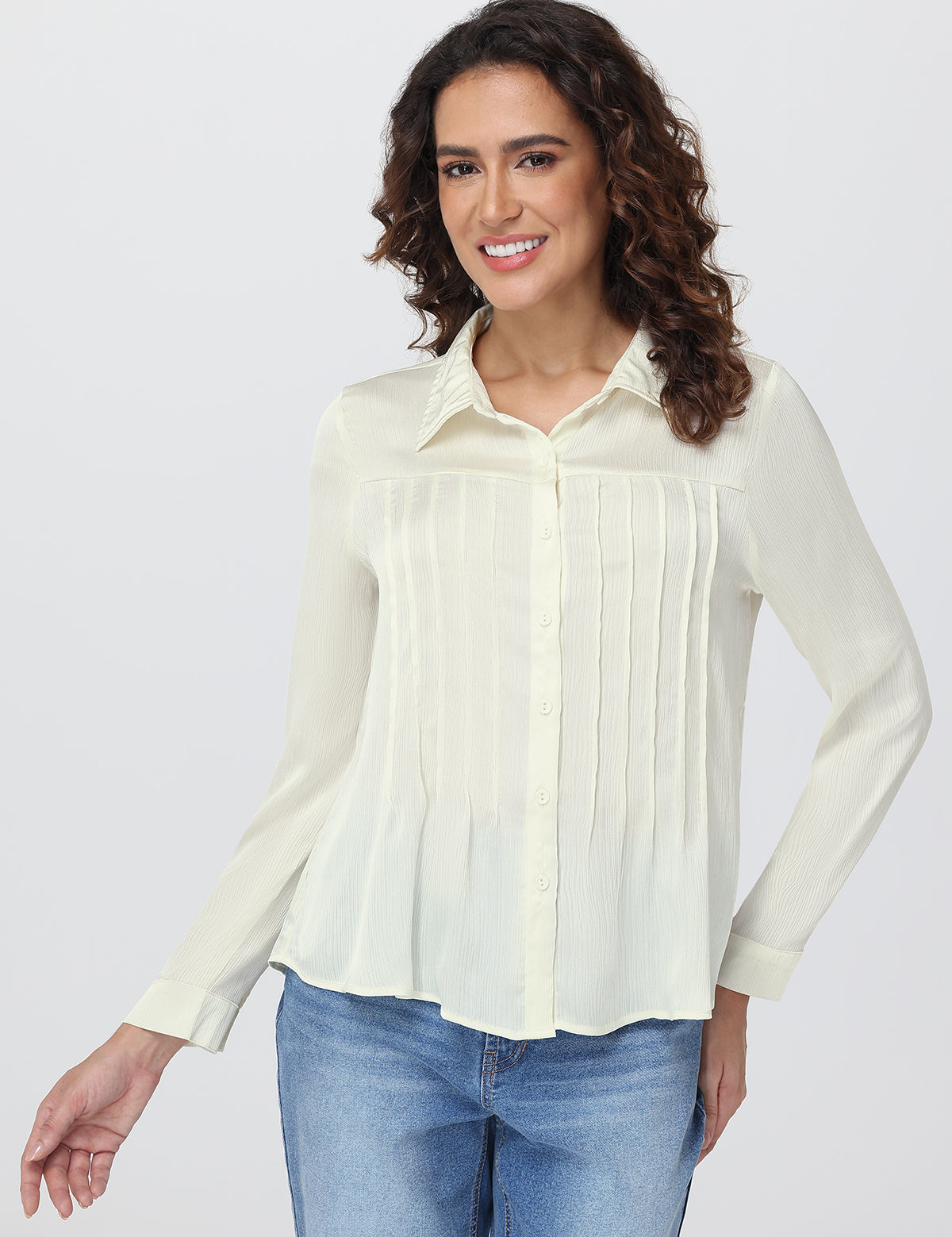 Woman wearing a light-colored blouse and blue jeans on a white background