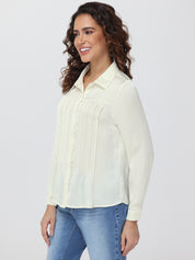 Woman wearing a light-colored shirt and blue jeans on a white background